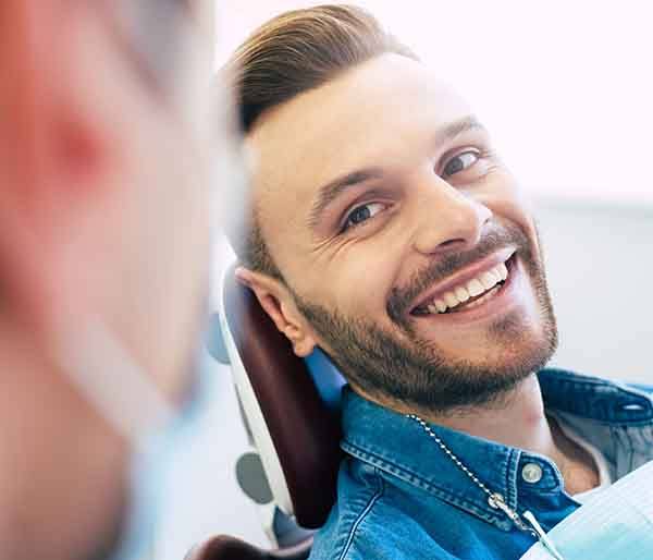 Patient with straight teeth smiling at dentist