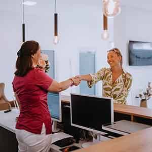Dental receptionist and patient shaking hands