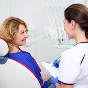 Smiling, mature woman talking to dental team member