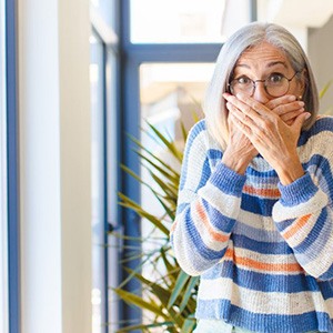 a woman covering her mouth due to tooth loss