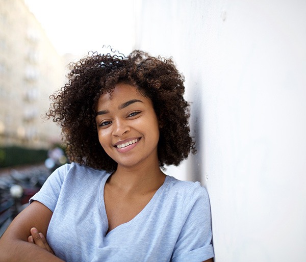 Woman leaning against a wall and smiling