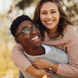 Couple wearing sweaters smiling and laughing outside