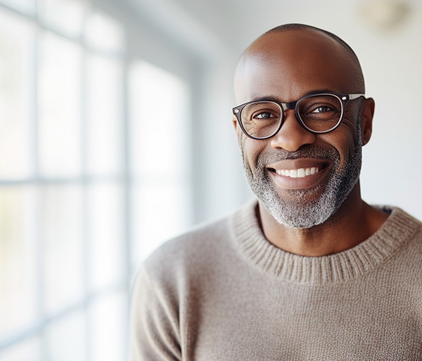 Smiling man in black glasses and brown sweater