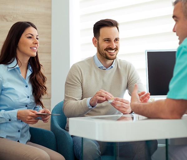 Dentist and couple talking in dental office