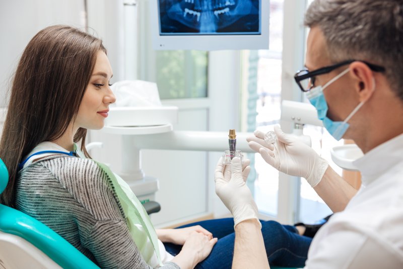 A dentist showing a dental implant to his patient